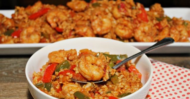 A photo of Shrimp and Rice in a white bowl with a full plate of the recipe in the back.